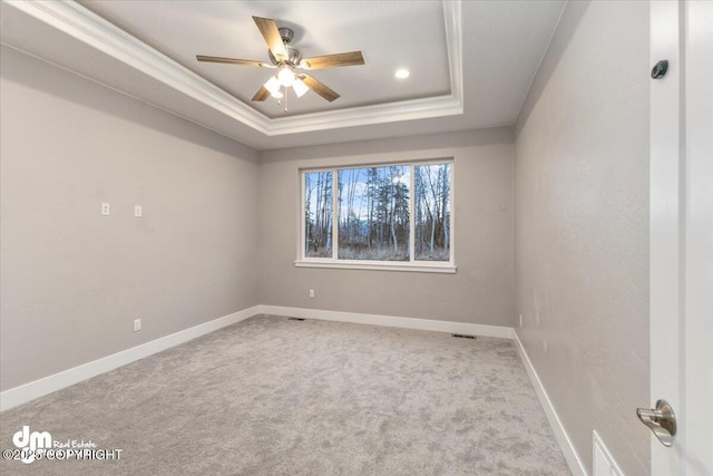 spare room with light carpet, ornamental molding, a raised ceiling, and ceiling fan