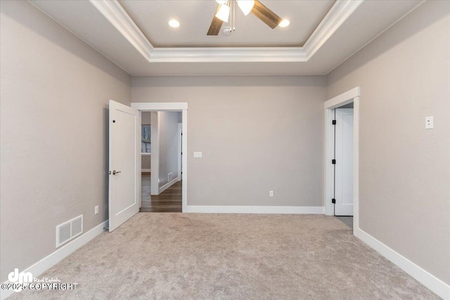 carpeted empty room with ceiling fan, ornamental molding, and a tray ceiling