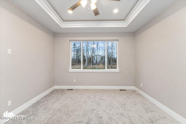 unfurnished room with ornamental molding, a raised ceiling, ceiling fan, and carpet