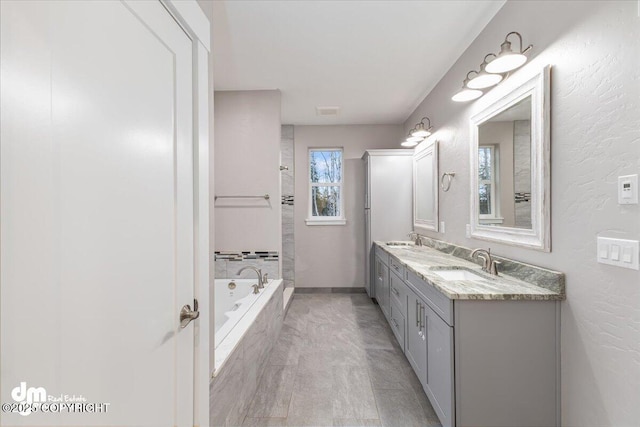 bathroom with vanity and tiled tub