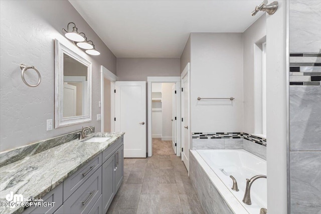 bathroom with vanity and tiled bath