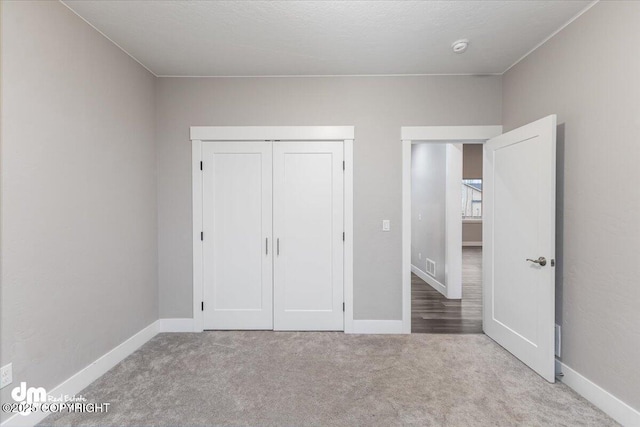 unfurnished bedroom with light colored carpet and a closet