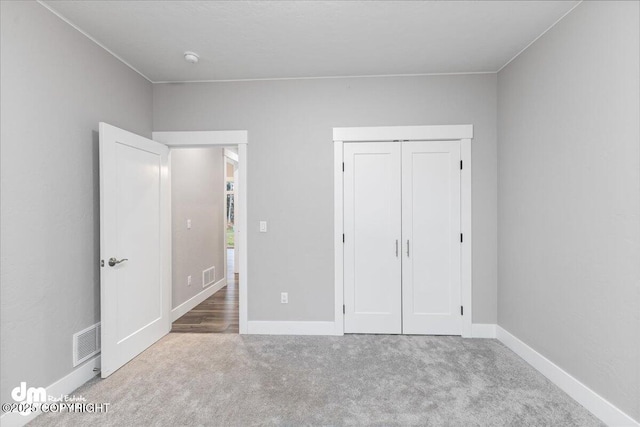 unfurnished bedroom with light colored carpet and a closet