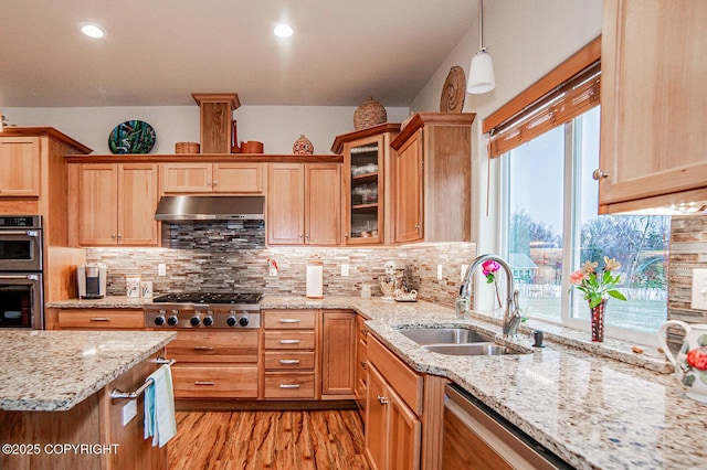 kitchen featuring pendant lighting, sink, light stone counters, and appliances with stainless steel finishes