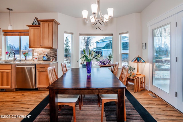 dining room with an inviting chandelier, sink, and light hardwood / wood-style floors