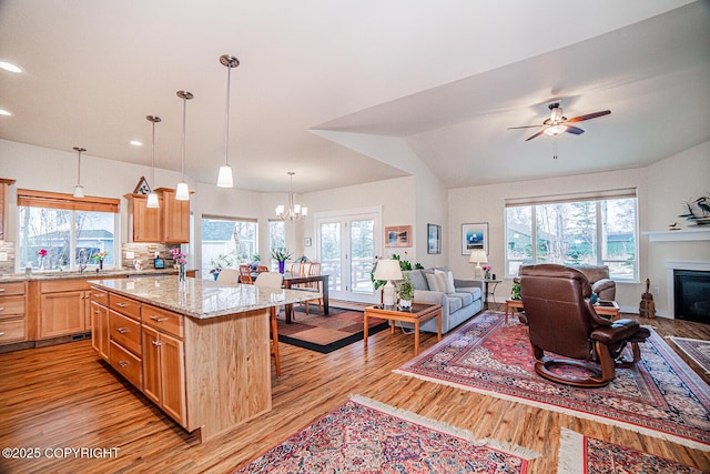 kitchen featuring pendant lighting, a kitchen island, light stone countertops, a kitchen bar, and vaulted ceiling