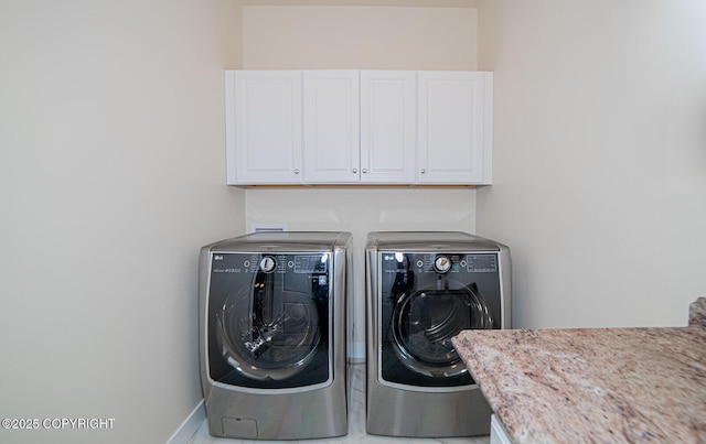 clothes washing area with separate washer and dryer and cabinets