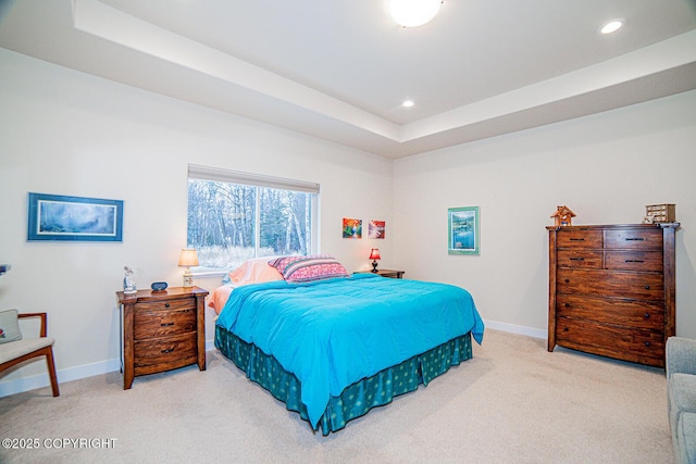 bedroom with a raised ceiling and light carpet