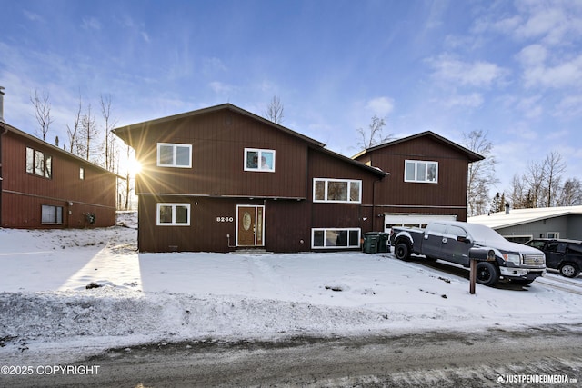 snow covered back of property featuring a garage