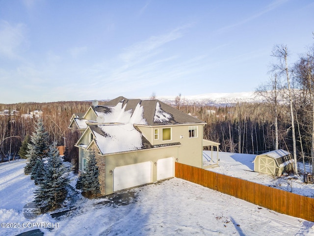 view of snow covered exterior with a garage and a storage unit