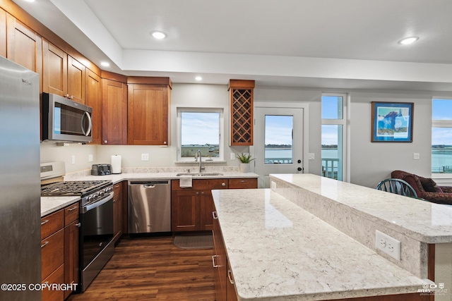 kitchen with appliances with stainless steel finishes, a center island, a water view, and a sink