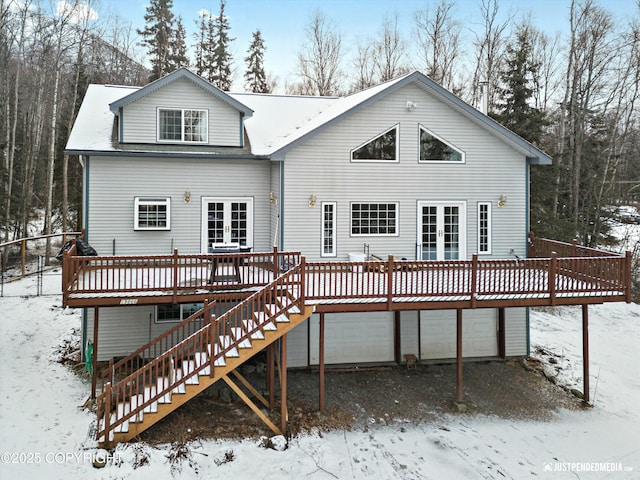 snow covered house with a garage and a wooden deck