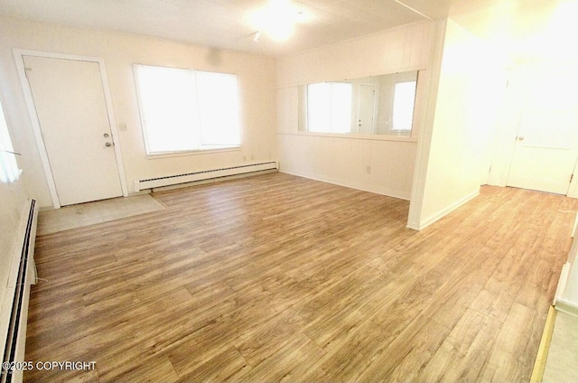 unfurnished room with baseboard heating and light wood-type flooring