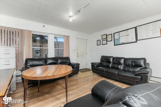 living room with track lighting, hardwood / wood-style floors, and a baseboard heating unit