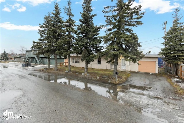 view of property hidden behind natural elements featuring a garage