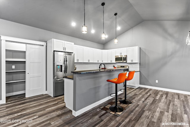 kitchen with dark hardwood / wood-style flooring, appliances with stainless steel finishes, white cabinetry, high vaulted ceiling, and an island with sink