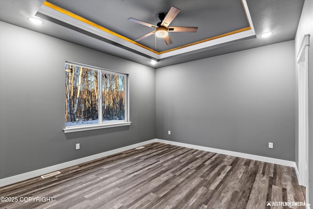 unfurnished room with ceiling fan, hardwood / wood-style flooring, a tray ceiling, and crown molding