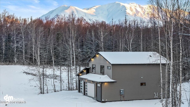 view of snowy exterior with a garage and a mountain view