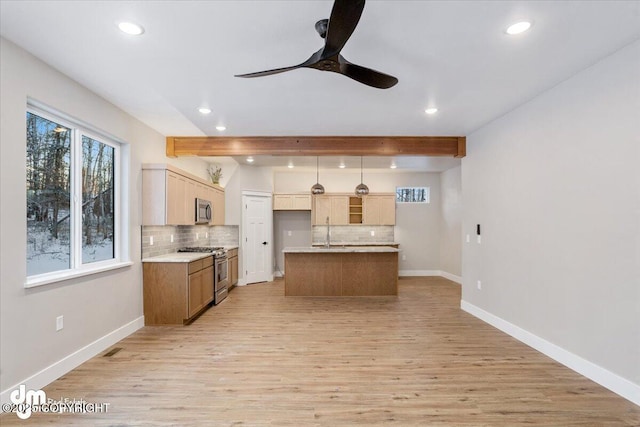 kitchen featuring tasteful backsplash, decorative light fixtures, a center island with sink, and appliances with stainless steel finishes