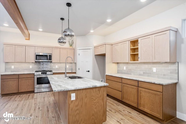 kitchen featuring sink, appliances with stainless steel finishes, a kitchen island with sink, light stone countertops, and decorative light fixtures