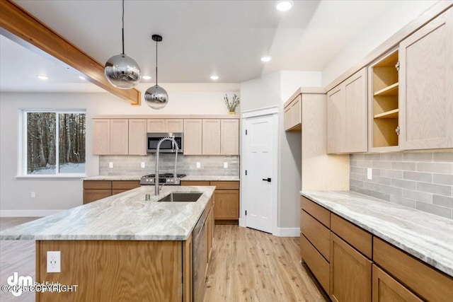 kitchen featuring light stone counters, a kitchen island with sink, hanging light fixtures, and light brown cabinets