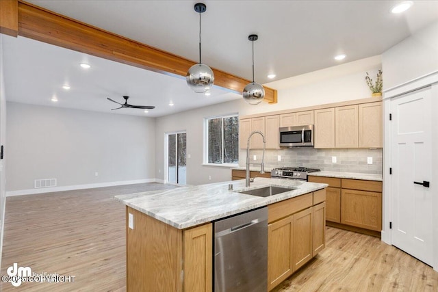 kitchen featuring pendant lighting, sink, appliances with stainless steel finishes, a center island with sink, and decorative backsplash