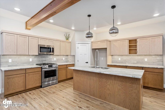 kitchen with sink, light stone counters, hanging light fixtures, stainless steel appliances, and a kitchen island with sink