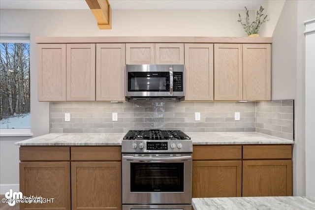 kitchen with light brown cabinetry, decorative backsplash, light stone countertops, and appliances with stainless steel finishes