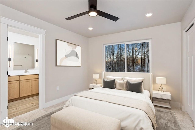 bedroom featuring ceiling fan, connected bathroom, sink, and light carpet