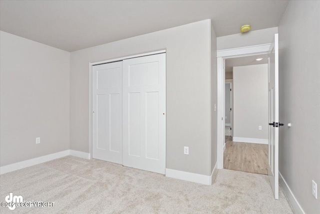 unfurnished bedroom featuring light colored carpet and a closet