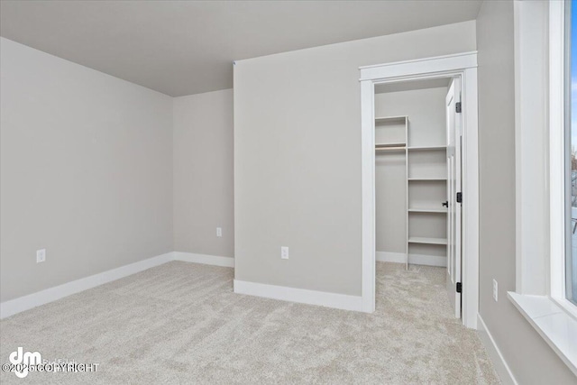 unfurnished bedroom with light colored carpet, a closet, and a walk in closet