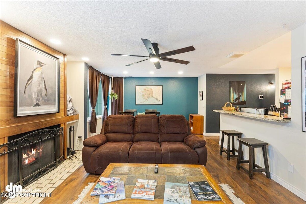 living room with dark wood-type flooring, ceiling fan, and a textured ceiling