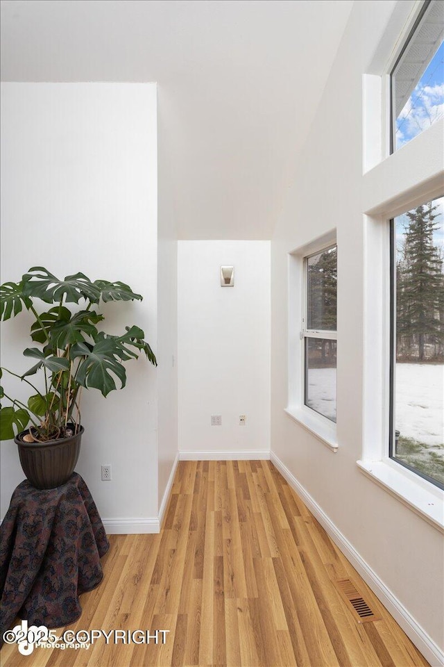 corridor featuring vaulted ceiling and light wood-type flooring