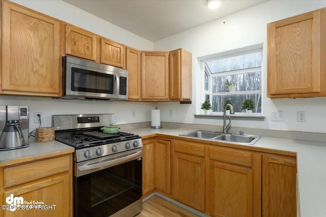 kitchen with sink, appliances with stainless steel finishes, and light wood-type flooring