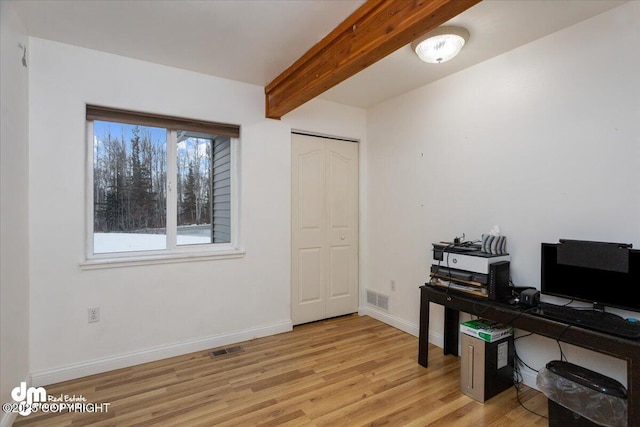 home office with light hardwood / wood-style flooring and beam ceiling