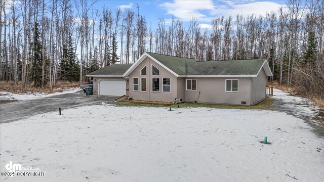 snow covered rear of property featuring a garage