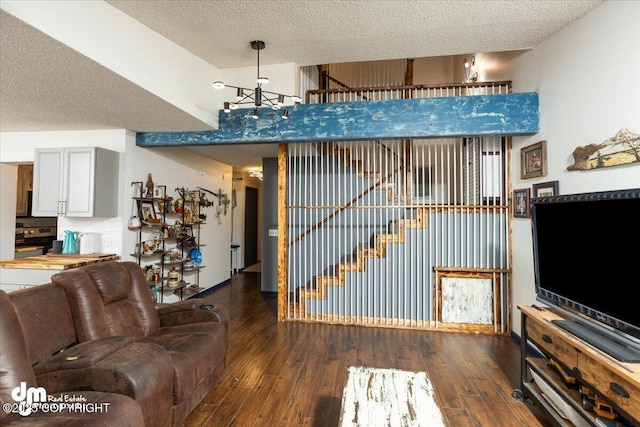 living room featuring a notable chandelier, dark wood-type flooring, and a textured ceiling