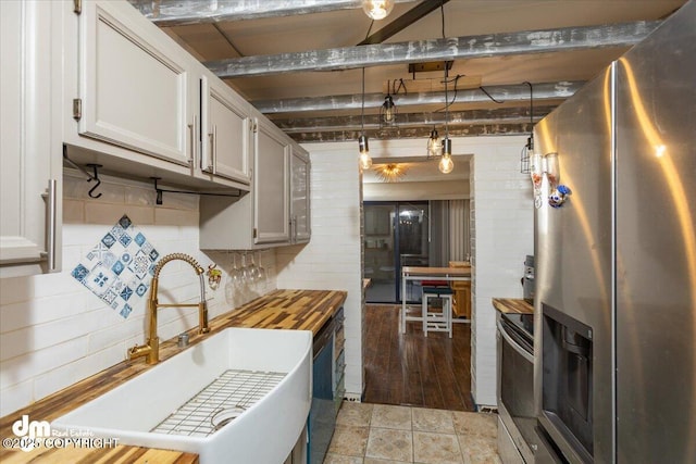 kitchen with sink, tasteful backsplash, appliances with stainless steel finishes, pendant lighting, and beam ceiling