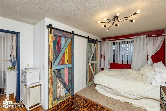 bedroom with an inviting chandelier, hardwood / wood-style floors, a barn door, and a textured ceiling