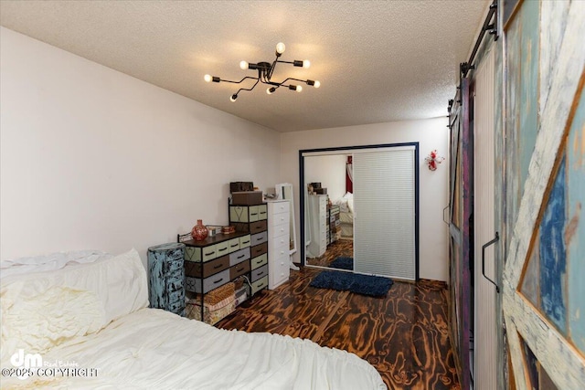 bedroom with dark hardwood / wood-style flooring, a barn door, and a textured ceiling