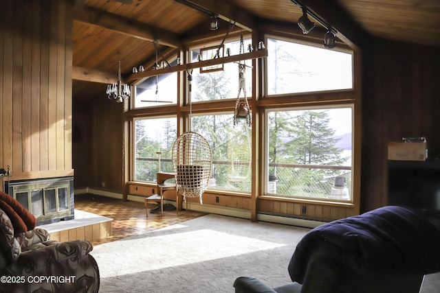 carpeted living room with lofted ceiling with beams, a notable chandelier, wooden walls, and rail lighting