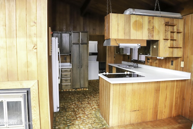 kitchen featuring kitchen peninsula, sink, wooden walls, and black electric cooktop