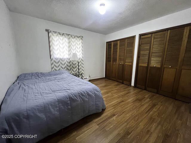 bedroom with multiple closets, dark wood-type flooring, and a textured ceiling