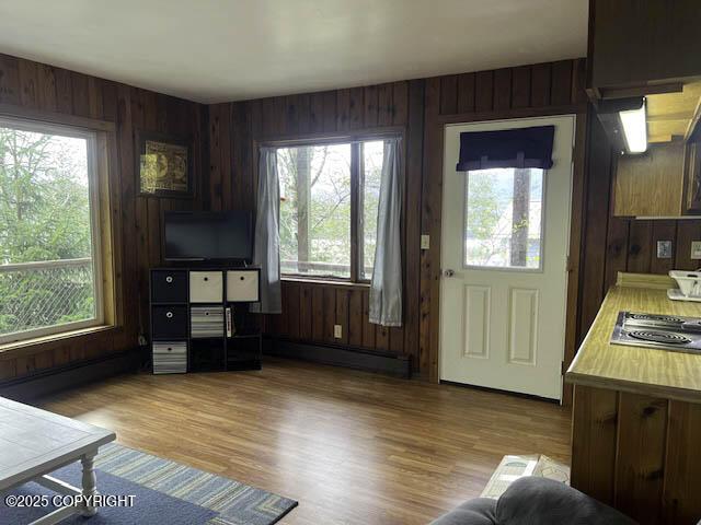 office featuring plenty of natural light, baseboard heating, wood walls, and light wood-type flooring