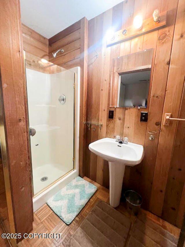 bathroom with an enclosed shower and wood walls