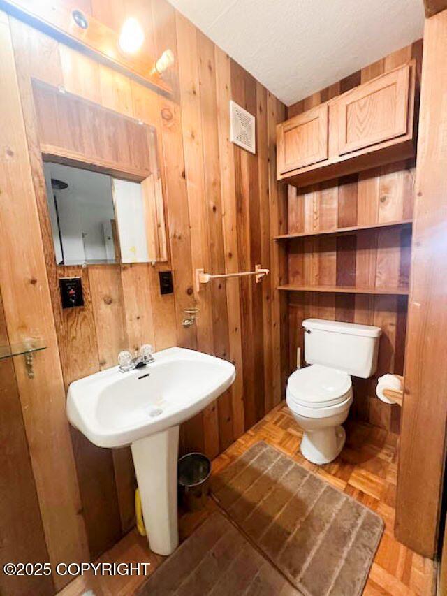 bathroom featuring sink, toilet, and wood walls