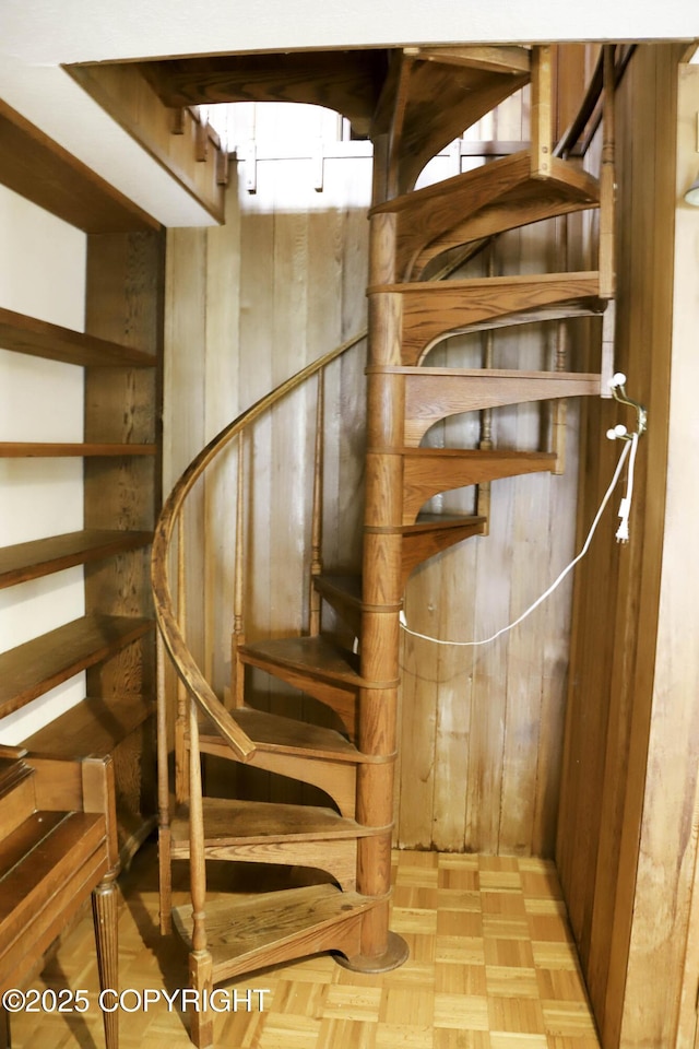 stairway with wood walls and parquet flooring