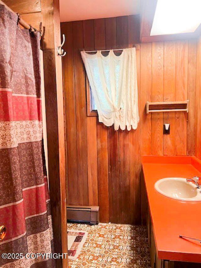 bathroom with vanity, wooden walls, and a baseboard radiator