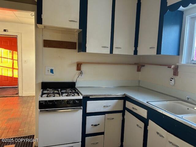 kitchen with sink, white cabinets, and gas range gas stove