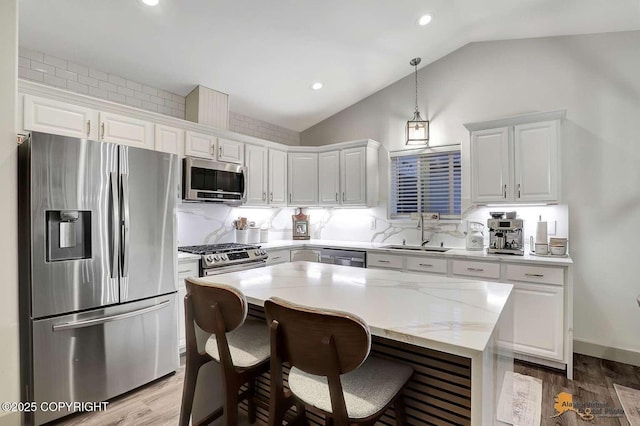 kitchen with stainless steel appliances, white cabinetry, decorative light fixtures, and sink